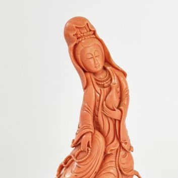 Statuette of Guanyin in red-orange coral, the lustral water vase in the left hand, the mala in the right. China, 20th century.