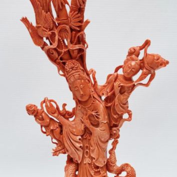 CHINA, 20th century Statuette in orange-pink coral, the goddess Guanyin holding the vase of lustral water