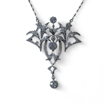 Collier pendentif en or gris 18k (750e) et platine, stylisant des volutes végétales, ornée de diamants taille ancienne